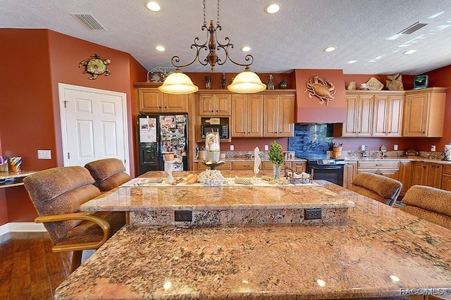 kitchen with hanging light fixtures, a center island, a breakfast bar, and black appliances