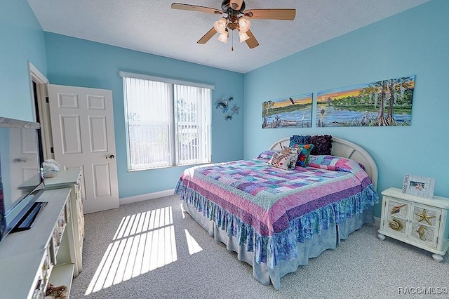 bedroom featuring ceiling fan, light colored carpet, and a textured ceiling