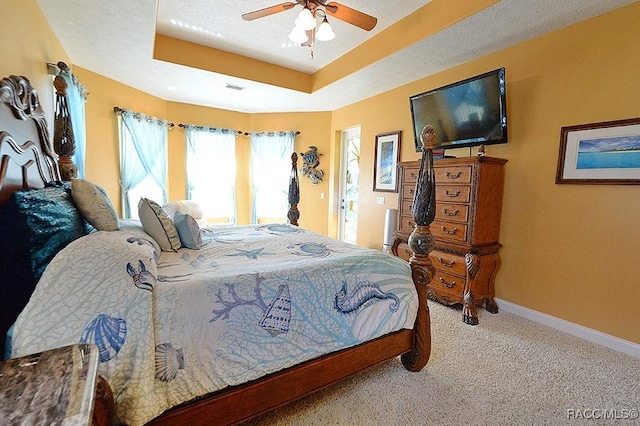 carpeted bedroom featuring a tray ceiling, a textured ceiling, and ceiling fan