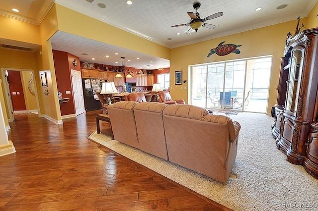 living room with ornamental molding, dark wood-type flooring, ceiling fan, and a textured ceiling