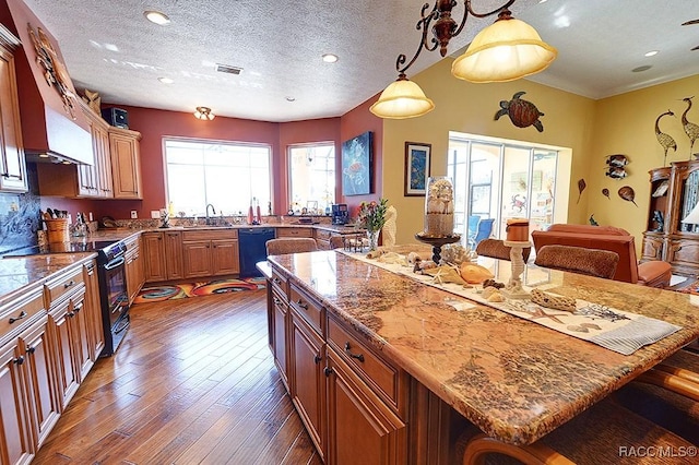 kitchen featuring a breakfast bar, a center island, hanging light fixtures, black dishwasher, and range with electric cooktop