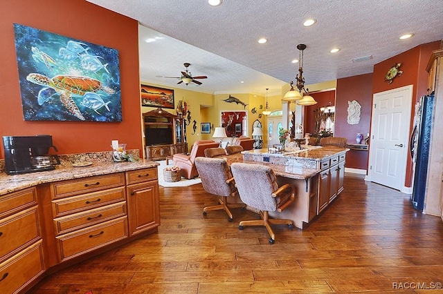 kitchen featuring light stone counters, dark hardwood / wood-style flooring, hanging light fixtures, and a textured ceiling