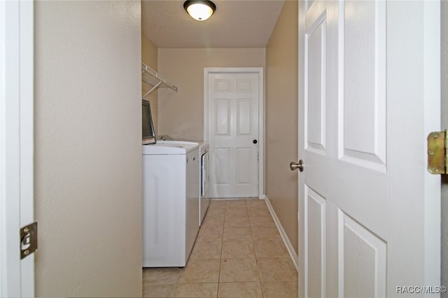 laundry area featuring washing machine and dryer, light tile patterned floors, and a textured ceiling