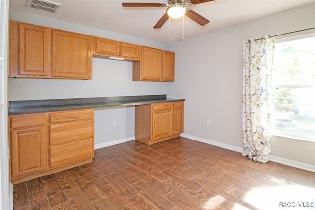 kitchen with ceiling fan, dark hardwood / wood-style flooring, and built in desk