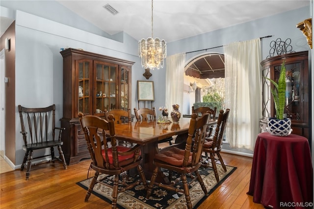 dining area with a chandelier, light wood-type flooring, and lofted ceiling