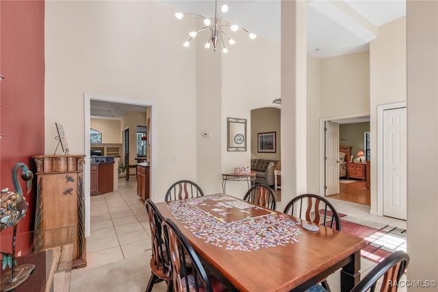 tiled dining area featuring a towering ceiling and a notable chandelier