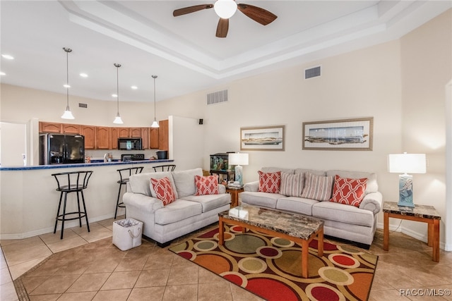 tiled living room featuring a raised ceiling and ceiling fan