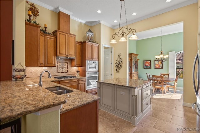 kitchen featuring pendant lighting, sink, a kitchen island, light stone counters, and kitchen peninsula