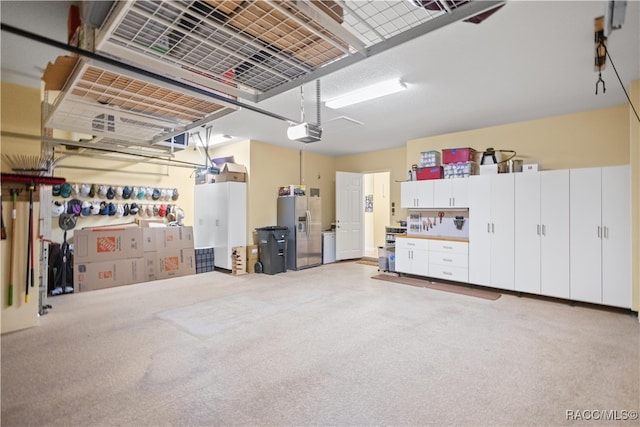 garage featuring a workshop area, stainless steel fridge with ice dispenser, and a garage door opener