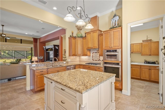 kitchen with sink, a center island, hanging light fixtures, ornamental molding, and appliances with stainless steel finishes