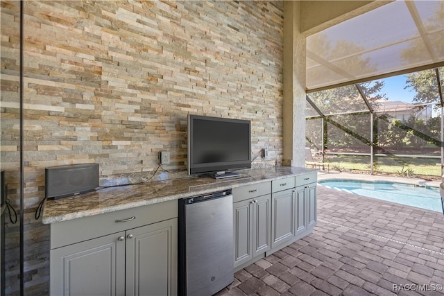 view of patio / terrace featuring glass enclosure and exterior kitchen