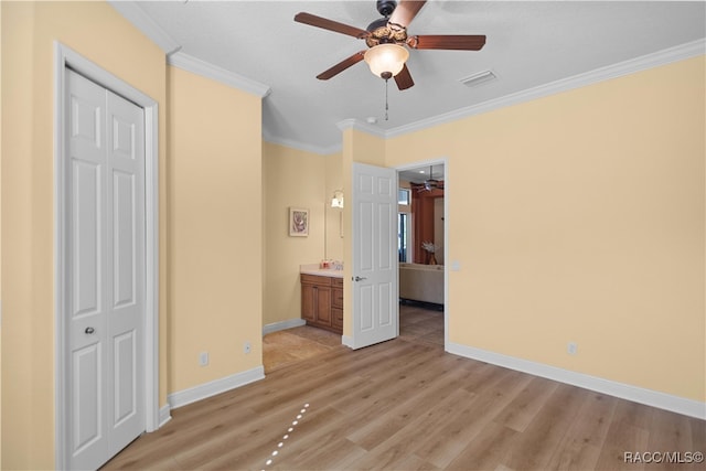 unfurnished bedroom with ensuite bath, ceiling fan, ornamental molding, a closet, and light wood-type flooring