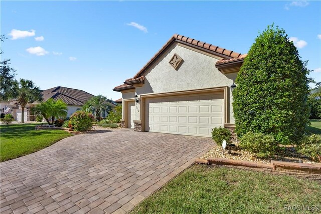 mediterranean / spanish-style home featuring a front yard and a garage