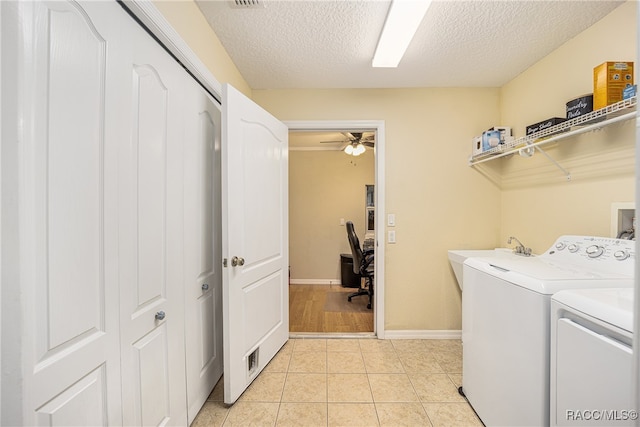 washroom with a textured ceiling, ceiling fan, sink, light tile patterned floors, and independent washer and dryer