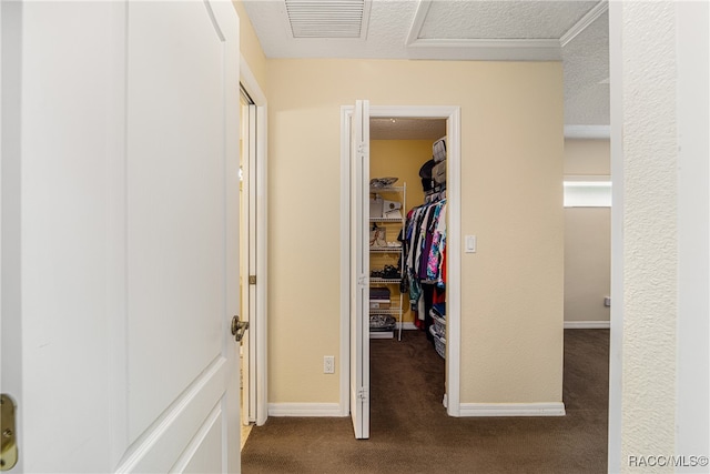 corridor with a textured ceiling and dark colored carpet