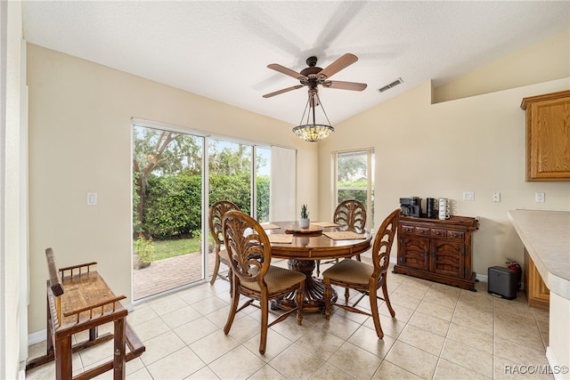 dining room with ceiling fan, lofted ceiling, a textured ceiling, and light tile patterned floors