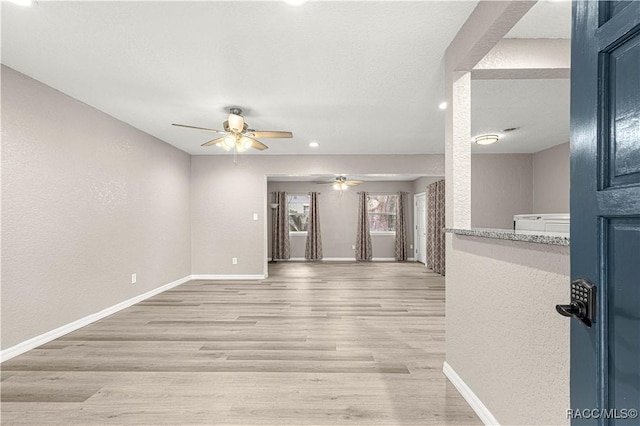 unfurnished living room with a textured ceiling, light hardwood / wood-style flooring, and ceiling fan