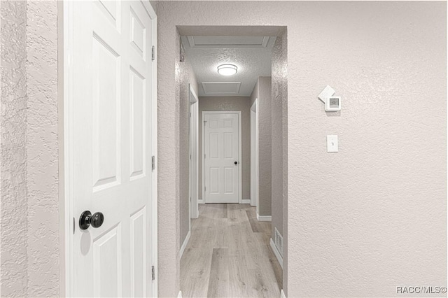 hall featuring light hardwood / wood-style floors and a textured ceiling