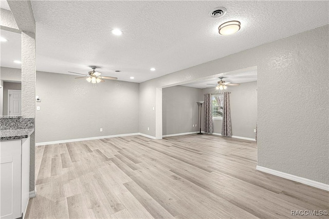 unfurnished living room with ceiling fan, a textured ceiling, and light wood-type flooring