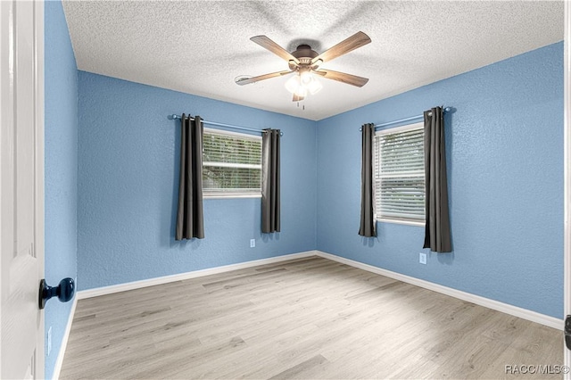 spare room with a textured ceiling, light wood-type flooring, and ceiling fan