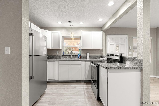 kitchen with sink, stainless steel appliances, white cabinetry, and dark stone countertops