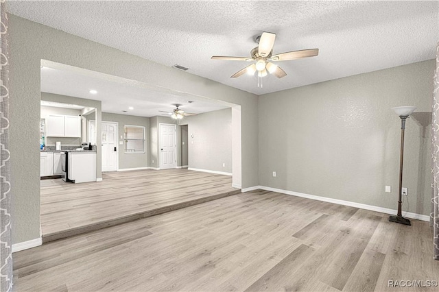 unfurnished living room featuring a textured ceiling, light wood-type flooring, and ceiling fan