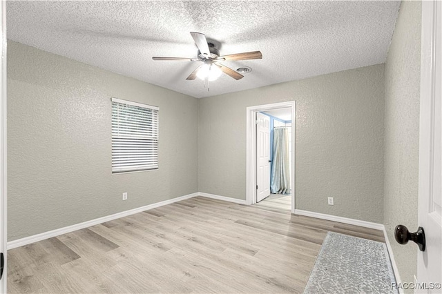 spare room featuring a textured ceiling, light wood-type flooring, and ceiling fan