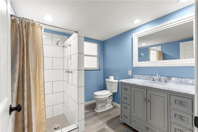 bathroom featuring hardwood / wood-style floors, vanity, a shower with curtain, toilet, and a textured ceiling