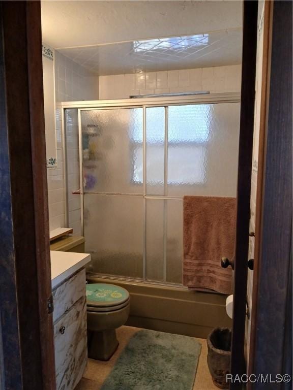 bathroom with enclosed tub / shower combo, vanity, and toilet