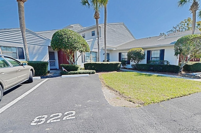 view of front of home featuring uncovered parking, a front yard, and stucco siding