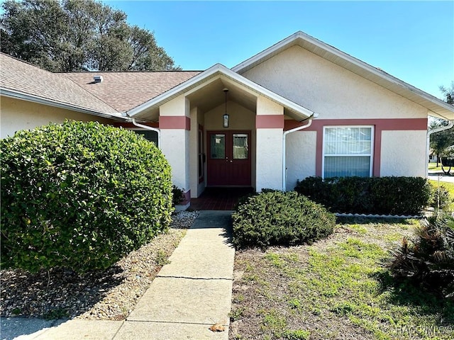 view of front of property with stucco siding, french doors, and roof with shingles