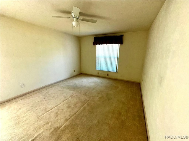 carpeted spare room with baseboards and ceiling fan