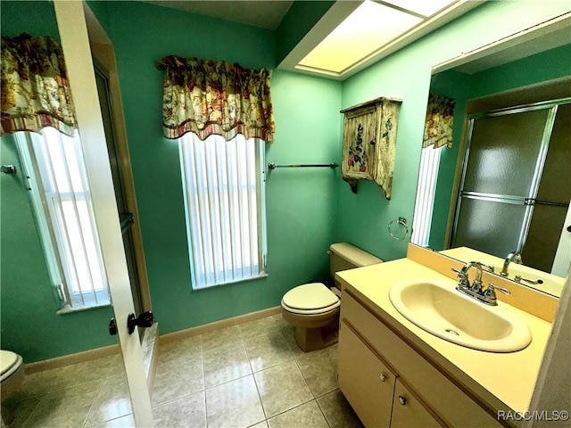 bathroom with tile patterned floors, toilet, a stall shower, baseboards, and vanity