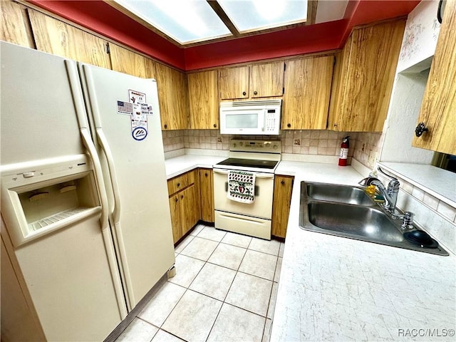 kitchen with a sink, white appliances, backsplash, and light countertops