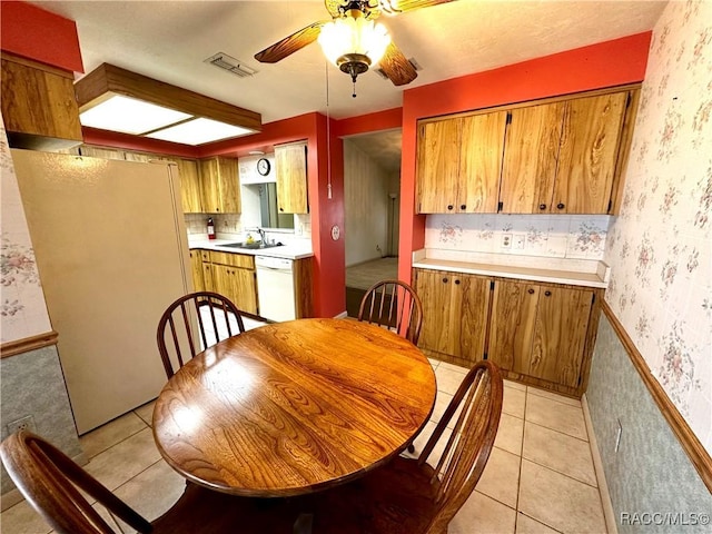 dining area featuring visible vents, a ceiling fan, wainscoting, wallpapered walls, and light tile patterned floors