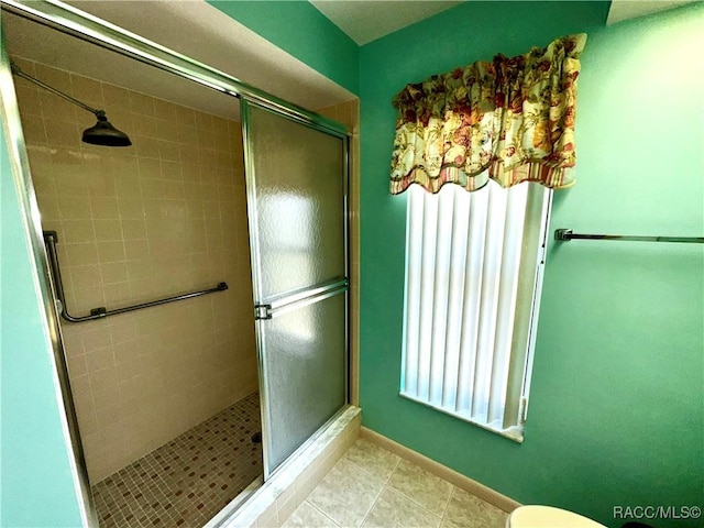 full bath with tile patterned floors, toilet, baseboards, and a stall shower