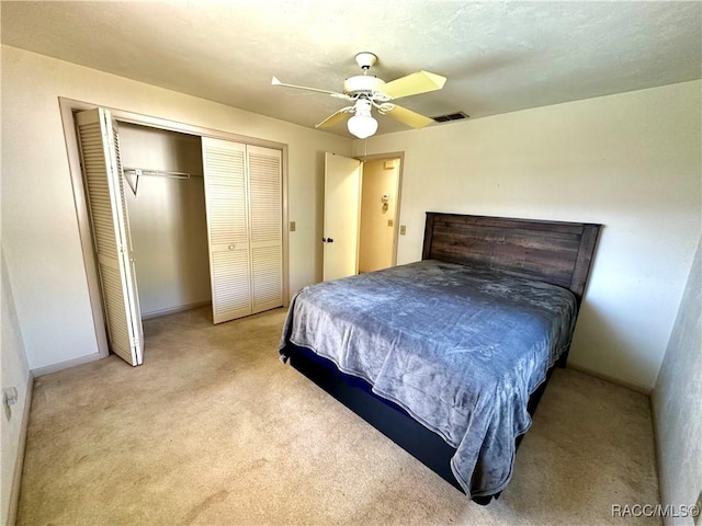 carpeted bedroom with a closet, visible vents, and a ceiling fan