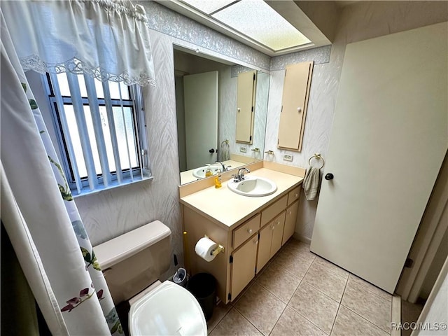 bathroom with tile patterned floors, toilet, vanity, and a textured wall