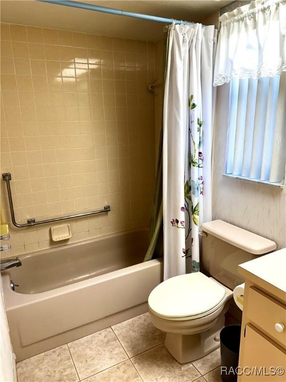 bathroom with vanity, tile patterned floors, shower / bath combination with curtain, and toilet