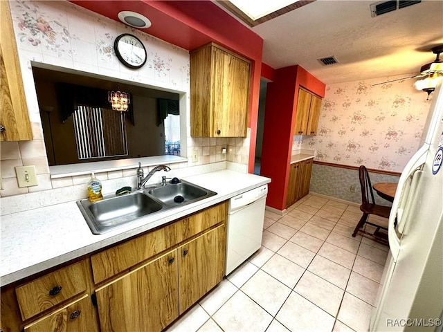 kitchen with wallpapered walls, light countertops, light tile patterned floors, white appliances, and a sink