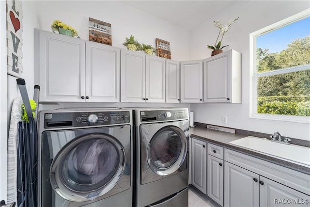 washroom with cabinets, washing machine and dryer, sink, and a wealth of natural light