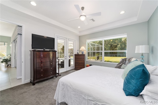 bedroom featuring access to outside, french doors, ceiling fan, a tray ceiling, and light colored carpet