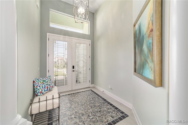 tiled foyer entrance with french doors and a chandelier