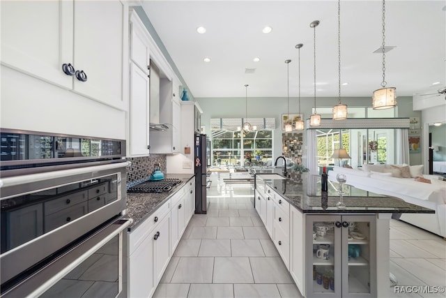 kitchen with decorative light fixtures, a spacious island, white cabinetry, and sink