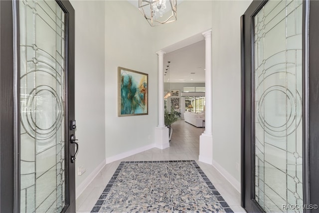 entryway featuring light tile patterned floors, decorative columns, and an inviting chandelier