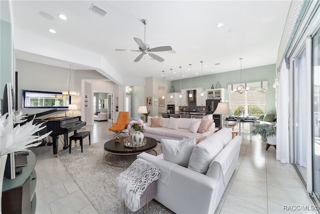 living room featuring ceiling fan with notable chandelier and light tile patterned floors