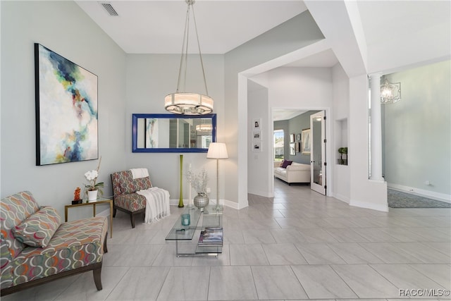 living area with ornate columns, light tile patterned floors, and an inviting chandelier