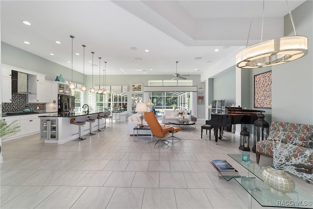 tiled living room featuring ceiling fan with notable chandelier and sink