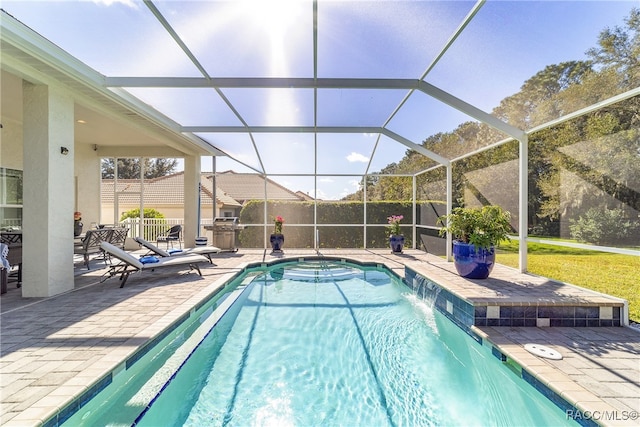 view of swimming pool with pool water feature, glass enclosure, and a patio area