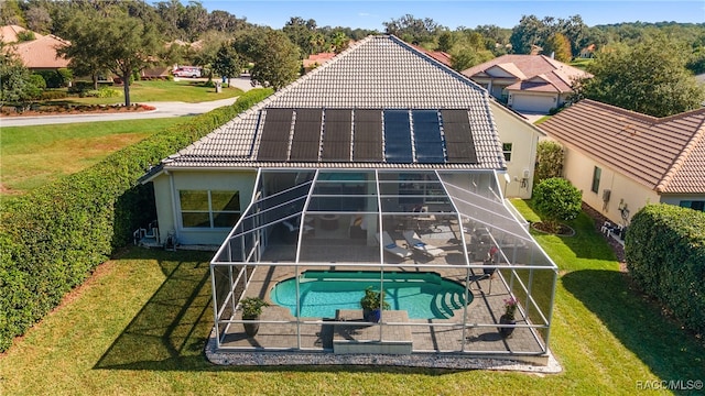 back of house featuring solar panels, a patio, a lanai, and a lawn